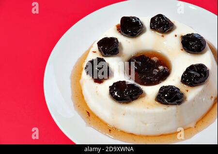 Köstliches traditionelles brasilianisches Dessert, bekannt als 'manjar de Coco Branco' mit Pflaumensoße. Traditionell zu Weihnachten und Neujahr in Brasilien konsumiert. Stockfoto