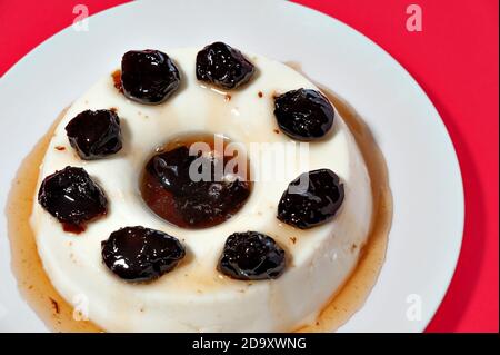 Köstliches traditionelles brasilianisches Dessert, bekannt als 'manjar de Coco Branco' mit Pflaumensoße. Traditionell zu Weihnachten und Neujahr in Brasilien konsumiert. Stockfoto