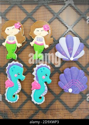 Hausgemachte Puderzucker-Kekse in Form einer Meerjungfrau, Auster und Seepferdchen. Draufsicht. Vertikale Aufnahme. Stockfoto
