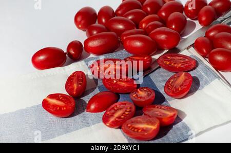 Tomaten, ganz und halbiert auf einer Küchenserviette. Stockfoto