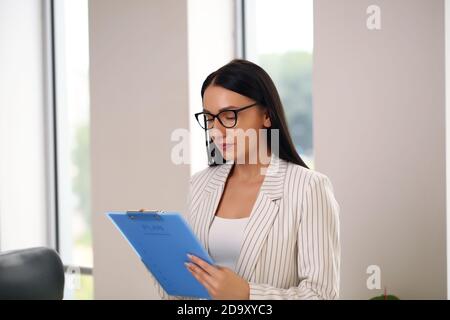 Junge Geschäftsfrau hält einen Ordner, Brünette in einem Anzug Stockfoto
