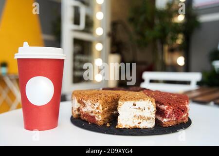 Papiertasse Kaffee mit Dessert. Kaffee mit Kuchen auf weißem Tisch Stockfoto