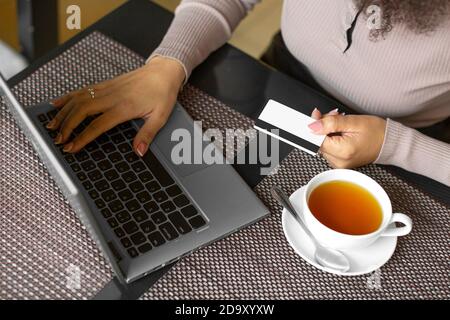 Nahaufnahme einer Frau, die Kartenzahlung über Online-Laptop-Anwendung in einem Café macht. E-Commerce-Konzept. Stockfoto