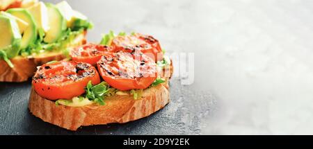 Bruschetta mit Tomaten und Mozzarella. Auf dunklem Hintergrund. Bruschetta mit Avocado und Feta. Appetitliche Sandwiches mit gegrillten Tomaten. Italienisch Stockfoto