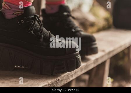 Schwarze Sportschuhe für Damen. Weibliche Beine in schwarzen, legeren Sneakers. Bequeme Damenschuhe. Lässige Damenmode. Stockfoto