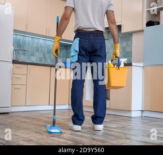 Mann, der Mopp und Eimer mit Reinigungsmaterial hält Stockfoto