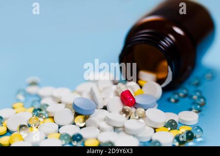 Medizinische Flasche und Medikationspillen verschüttet auf pastellblauen Hintergrund. Gesundheitswesen, Pharmazie, Medizin Konzept Stockfoto