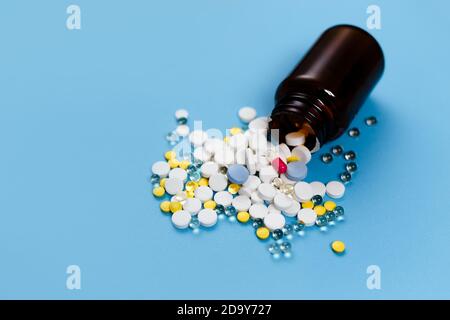 Medizinische Flasche und Medikationspillen verschüttet auf pastellblauen Hintergrund. Gesundheitswesen, Pharmazie, Medizin Konzept Stockfoto