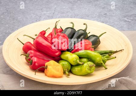 Gemischte rote und grüne frische Chilischoten in einer Schüssel auf dem Tisch Stockfoto