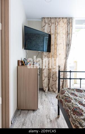 Anapa, Russland - 23. August 2020: Ein Fragment des Inneren eines kleinen Schlafzimmers, in der Ecke gibt es einen Nachttisch und einen Fernseher Stockfoto