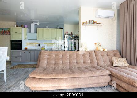 Anapa, Russland - 23. August 2020: Interieur einer geräumigen Küche kombiniert mit einem Wohnzimmer mit einem großen Sofa Stockfoto