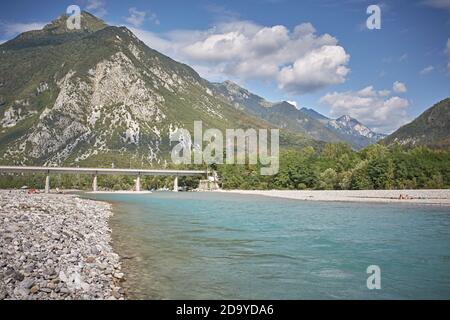 Venzone, Italien, August 2019. Der Fluss Tagliamento führt durch die Stadt mit der Brücke im Hintergrund. Stockfoto