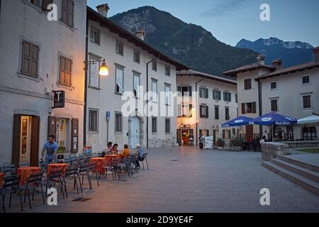 Venzone, Italien, August 2019. Menschen sitzen in einer Bar bei Sonnenuntergang auf der Via Glizoio di Mels, im Zentrum der Stadt. Stockfoto