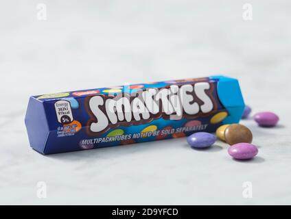 LONDON, UK - 21. OKTOBER 2020: Rohrcontainer von Smarties Schokolade überzogen Süßigkeiten auf Marmorbrett Hintergrund. Stockfoto
