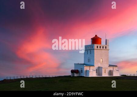 Tolle Abendansicht des Dyrholaey Lighthouse am Cape Dyrholaey, Südküste Islands. Große lila Sonnenuntergang leuchtet auf dem Hintergrund. Landschaftsfotografie Stockfoto