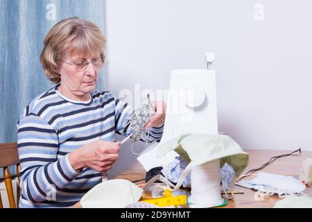 Blonde ältere Dame macht Gesichtsmasken zu Hause. Stockfoto