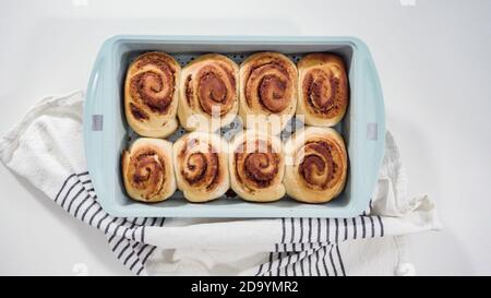 Flach liegend. Glasur frisch gebackene Zimtschnecken in einer blauen Backform. Stockfoto