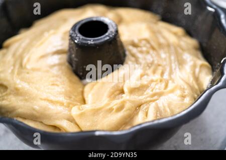 Zitronenpfaumteig in einer gebrannten Backform, fertig zum Backen. Stockfoto