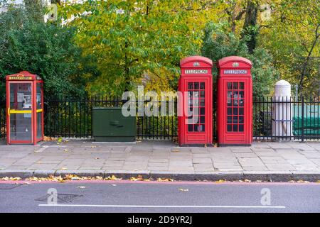 Rote Telefonzellen vor herbstlichen Blättern Stockfoto