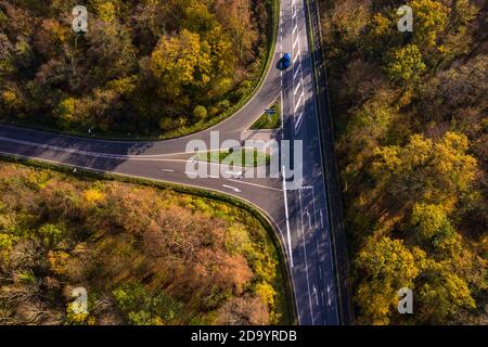 Eine Straße mit einer Kreuzung in einem Wald bedroht unsere Umwelt durch das Löschen von Bäumen Stockfoto