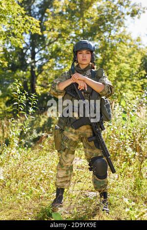 Leistungsstarke sportliche Frau Soldat bereit für den Kampf tragen schützende militärische Ausrüstung Waffe, Gewehr oder Waffe. In der wilden Natur Stockfoto