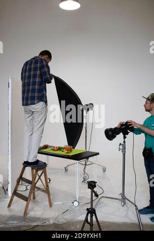 Food Fotografie Unterricht in einem Fotostudio macht ein Schüler auf einer Trittleiter eine flache Laie Stockfoto