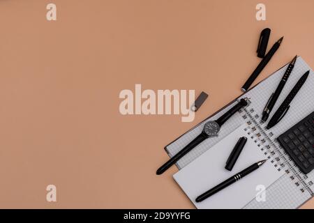 Moderne Büroarbeitsplatz mit leeren Notebooks, Stifte, Armbanduhr usb-Speicherkarte . Kopieren Sie den Raum auf dem Hintergrund der braunen Holzmaserung. Draufsicht Stockfoto
