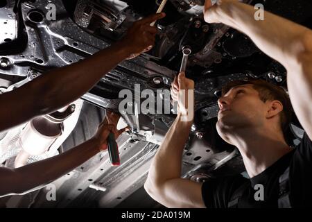 Zwei freundliche professionelle Auto-Mechaniker während der Arbeit, sind sie erfolgreich Reparatur Auto, lösen Probleme zusammen Stockfoto