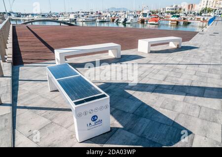 Bank mit Solarpanel und mobiles Ladegerät am Wasser in la Ampolla, Tarragona, Katalonien, Spanien Stockfoto