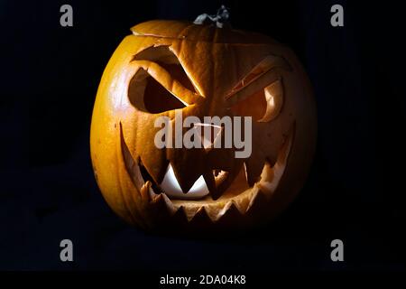 Jack O'Lantern beleuchtet Kürbis mit bösen Lächeln isoliert auf ein Schwarzer Hintergrund - Halloween Tradition Stockfoto