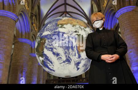 Canon Celia Thomson von der Gloucester Cathedral. Er hat die ganze Welt in seinen Händen, genauer gesagt die ganze Erde in der Gloucester Cathedral. Stockfoto