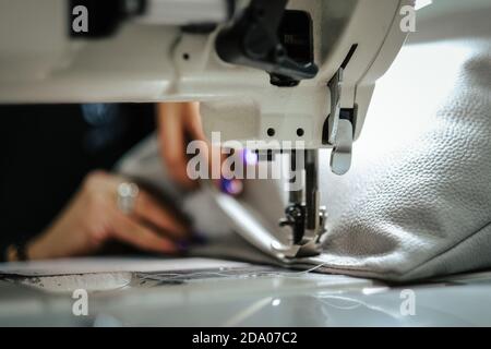 Nahaufnahme der weiblichen Hände, die graues Leder auf einer Maschine nähen Stockfoto