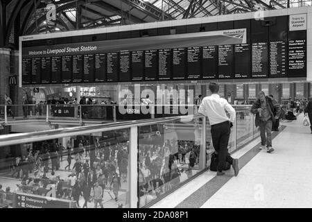 Pendler liest Abfahrtstafeln warten auf seinen Zug in Liverpool Street Station Stockfoto