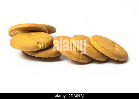 Süße knusprige leckere Weizenkekse auf isoliertem weißem Hintergrund verstreut Stockfoto