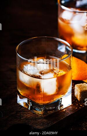 Old Fashioned - klassischer Alkoholcocktail mit Bourbon Whiskey, Bitter, Rohrzucker und Eis in Retro-Gläsern auf Vintage-Theke, Platz für Text Stockfoto