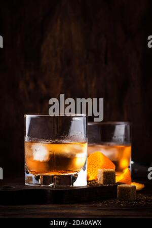 Old Fashioned - klassischer Alkoholcocktail mit Bourbon Whiskey, Bitter, Rohrzucker und Eis in Retro-Gläsern auf Vintage-Theke, Platz für Text Stockfoto