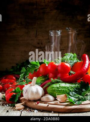 Frischer Knoblauch, Kirschtomaten, Gurke, Paprika, Petersilie, Dill auf einem hölzernen Schneidebrett, Gemüse für die mediterrane Ernährung, selektiver Fokus Stockfoto