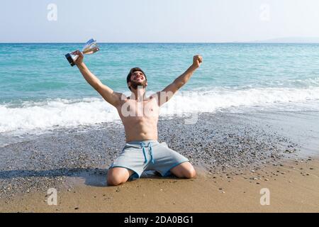 Männlicher Athlet hält einen Pokal hoch. Sieger Athlet zeigt Champion Trophäe Cup auf blauem Himmel Hintergrund. Sport, Leistung, Erfolg c Stockfoto