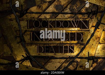 Lockdown induced deaths Text auf texturiertem Grunge Kupfer und Vintage Gold Hintergrund mit Stacheldraht Stockfoto