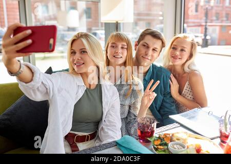 Überglücklich kaukasische Menschen posieren für Foto im Café zusammen, Selfie auf dem Smartphone nehmen, posieren für Foto im Café zusammen, Aufnahme Video für soziale Netzwerk, Spaß mit Freunden Stockfoto