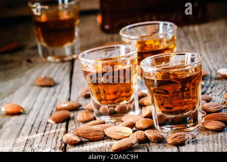 Italienischer Amaretto Likör mit trockenen Mandeln auf dem alten Holzhintergrund, selektiver Fokus Stockfoto