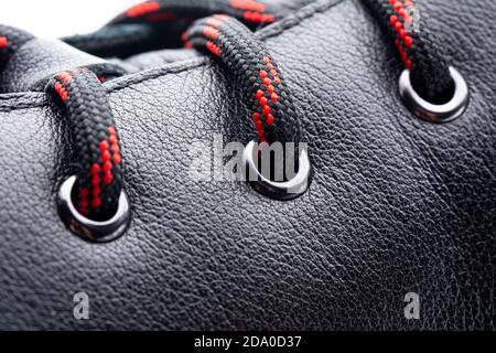 Nahaufnahme der rot-schwarzen Schnürsenkel auf Lederstiefel. Lässiges Modekonzept. Selektiver Fokus Stockfoto
