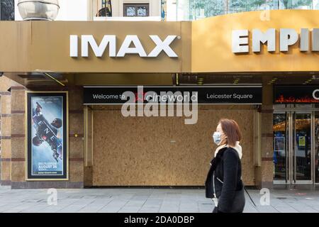 Fußgänger in Gesichtsmaske geht am IMAX-Theater am Leicester Square vorbei, das während der zweiten nationalen Sperre, London, am 7. November 2020, geschlossen wurde Stockfoto