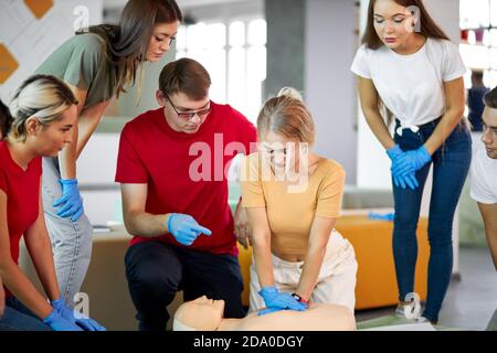 Gruppe von jungen kaukasischen Menschen lernen, wie man ein Leben sicher sitzen zusammen in der Lektion, diskutieren alle Techniken, mit Schaufensterpuppe ein Beispiel zu zeigen Stockfoto