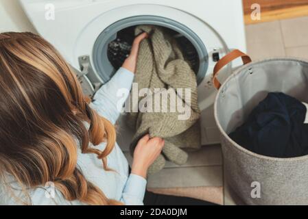 Frau, die Kleidung in die Waschmaschine einlädt. Stockfoto