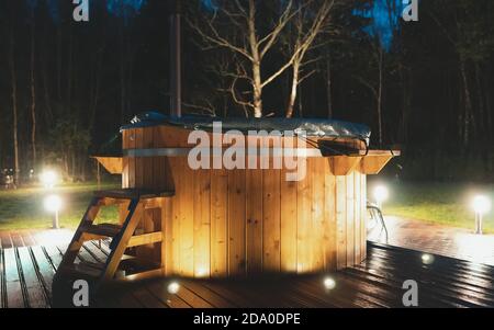 Holz-Whirlpool mit Kamin in der Nacht. Stockfoto