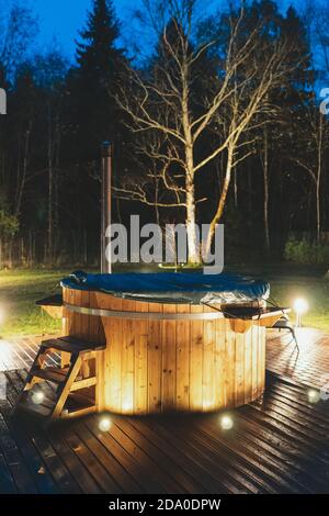 Holz-Whirlpool mit Kamin in der Nacht. Stockfoto