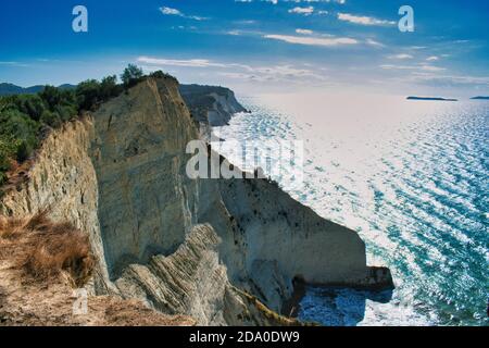 Weiße Klippe in Kerkyra Korfu Griechenland und himmlisch blaues Meer In einer Bucht mit braunem Sand und lehmigem Strand Stockfoto