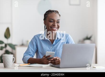 Selbständigkeit. Fröhliche Schwarze Millennial Frau Sitzt Am Arbeitsplatz Im Home Office Stockfoto