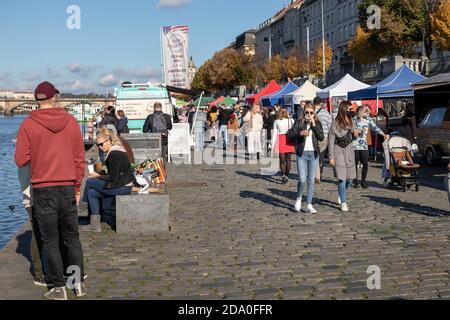 PRAG, TSCHECHISCHE REPUBLIK - 24. OKTOBER 2020: Menschen mit Gesichtsmasken wandern und entspannen auf dem Bauernmarkt Naplavka während der zweiten Welle des coro Stockfoto